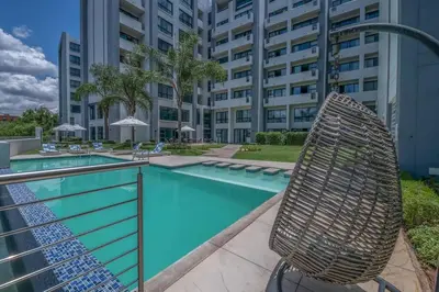 a swimming pool with a chair next to a building at Lovely 1 Bedroom Apartment in Pretoria