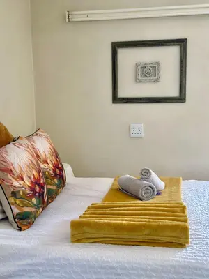 a bed with two towels and a picture on the wall at Guesthouse 52 in Groblersdal
