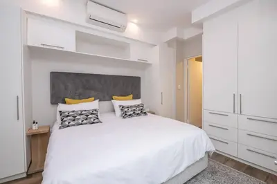 a white bedroom with a large white bed with pillows at 1 bedroom Apartment in Pretoria