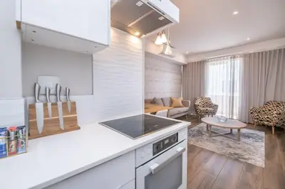 a kitchen with white appliances and a living room at 1 bedroom Apartment in Pretoria