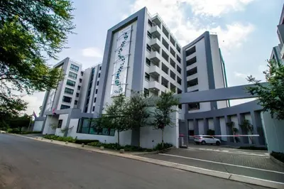 a large white building on the side of a street at 1 bedroom Apartment in Pretoria