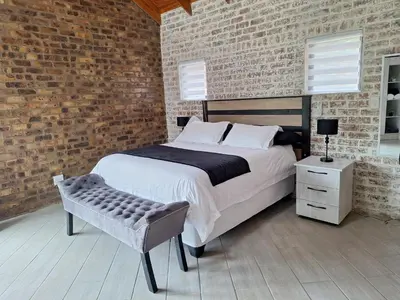 a bedroom with a large bed and a brick wall at Edel's Nest Nelspruit in Mataffin