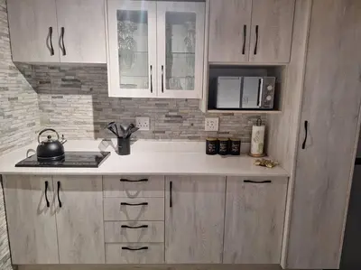 a kitchen with white cabinets and a tea kettle at Edel's Nest Nelspruit in Mataffin