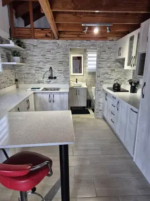 a kitchen with white cabinets and a red chair in it at Edel's Nest Nelspruit in Mataffin