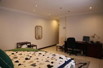 a bedroom with a bed and a desk and a mirror at Guest Home KS2E - Self Catering in Kempton Park