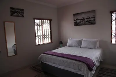 a bedroom with a bed and two windows at Guest Home KS2E - Self Catering in Kempton Park