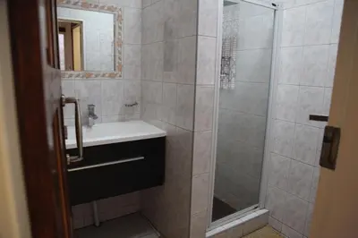 a bathroom with a shower with a sink and a mirror at Guest Home KS2E - Self Catering in Kempton Park