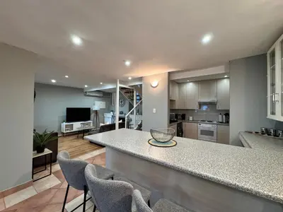 a kitchen and living room with a counter and chairs at Olives by Agnes in Hartbeespoort