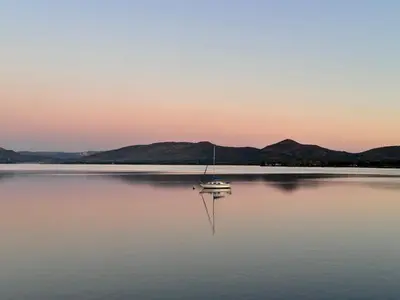 a sailboat in the middle of a lake at sunset at Olives by Agnes in Hartbeespoort