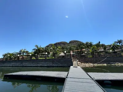 a dock in a body of water with palm trees at Olives by Agnes in Hartbeespoort
