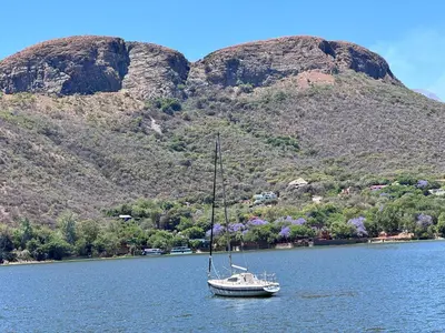 a boat in the water with mountains in the background at Olives by Agnes in Hartbeespoort