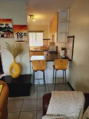 a kitchen with a counter and stools in a room at 2d - 50 No load shedding - 2 bedroom in Centurion