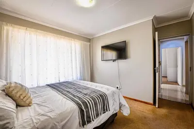 a bedroom with a bed and a window and a television at Secured Home in Centurion