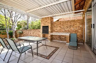 a patio with a table and chairs and a brick wall at Secured Home in Centurion