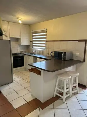 a kitchen with a counter and two stools in it at 2c - 4 No load shedding 2bed 2bath with garden in Centurion