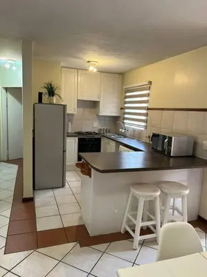 a kitchen with a refrigerator and two bar stools at 2c - 4 No load shedding 2bed 2bath with garden in Centurion