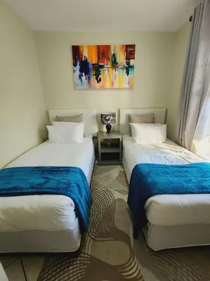 a room with two beds and a painting on the wall at 2b - 74 No load shedding - 2 bed home in Centurion