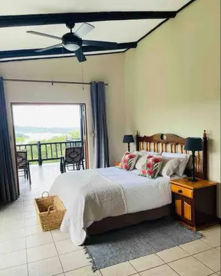 a bedroom with a large bed and a balcony at Sycamore Fig House next 2 Hulala Lodge in White River