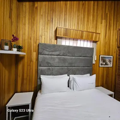 a bedroom with a bed with a wooden wall at Yello guest house chalets in Graskop