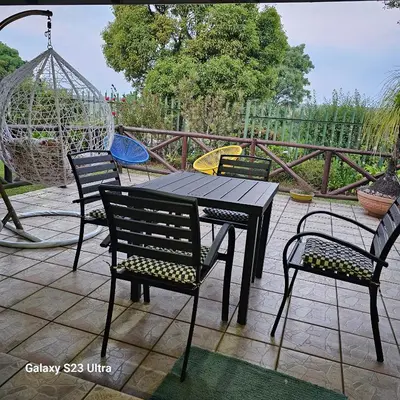 a table with four chairs and a swing on a patio at Yello guest house chalets in Graskop