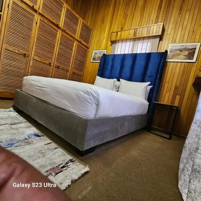 a bedroom with a large bed with a blue headboard at Yello guest house chalets in Graskop