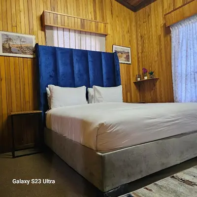 a bedroom with a large bed with a blue headboard at Yello guest house chalets in Graskop
