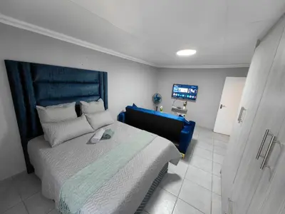 a bedroom with a large bed with a blue headboard at Azrisi Apartments in Kempton Park