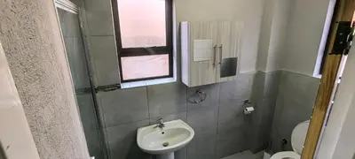 a bathroom with a sink and a toilet and a mirror at Azrisi Apartments in Kempton Park