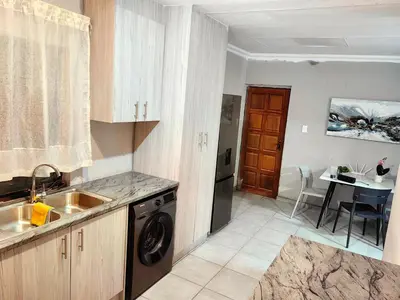 a kitchen with a sink and a washing machine in it at Azrisi Apartments in Kempton Park