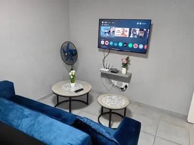 a living room with a blue couch and two tables at Azrisi Apartments in Kempton Park