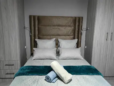 a bed with two towels on top of it at Azrisi Apartments in Kempton Park