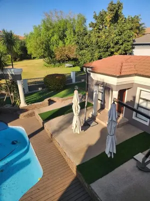 a house with a swimming pool and two umbrellas at Blue Valley Golf Estate in Centurion