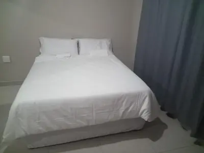 a white bed with white sheets and pillows at Elangeni Guest House in Mahubahuba