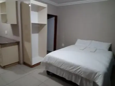 a bedroom with a white bed and a cabinet at Elangeni Guest House in Mahubahuba