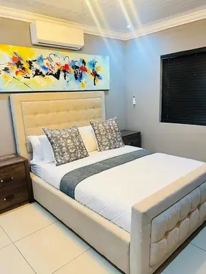 a bedroom with a bed with a painting on the wall at 9 on Burger Blue Waters in Polokwane