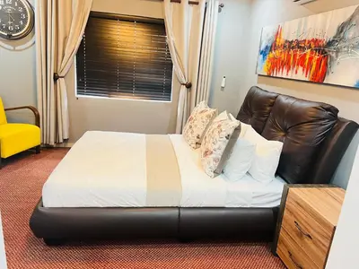 a bedroom with a bed and a leather couch at 9 on Burger Blue Waters in Polokwane
