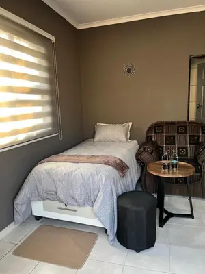 a bedroom with a bed and a table and a chair at Família BnB in Tekwane