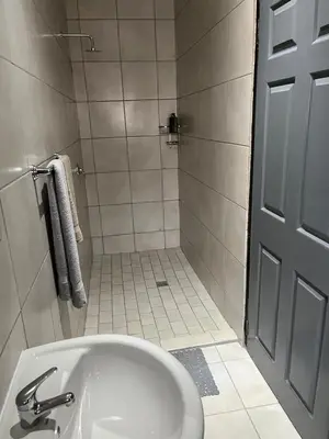 a white bathroom with a sink and a shower at Família BnB in Tekwane