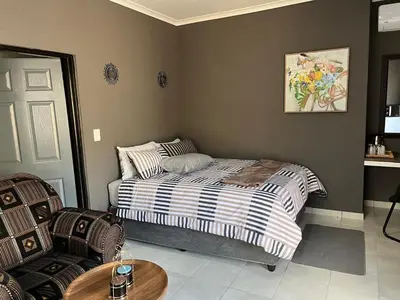 a bedroom with a bed and a table and chairs at Família BnB in Tekwane