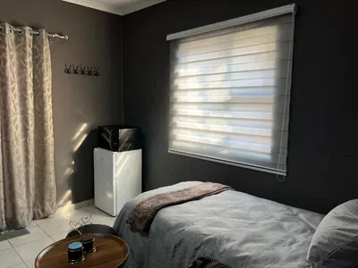 a bedroom with a bed and a table and a window at Família BnB in Tekwane