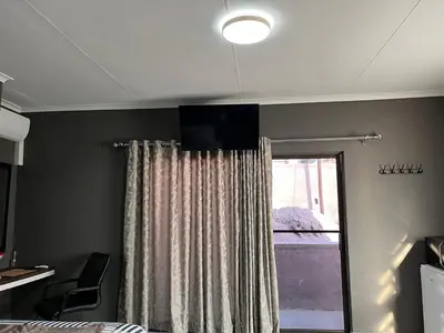 a bedroom with a curtain and a window at Família BnB in Tekwane