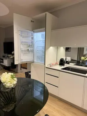 a kitchen with white cabinets and a glass table at Homely - 1 bedroom rental unit at Ellipse in Midrand
