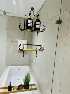 a bathroom with a bath tub and three bottles on a shelf at Homely - 1 bedroom rental unit at Ellipse in Midrand