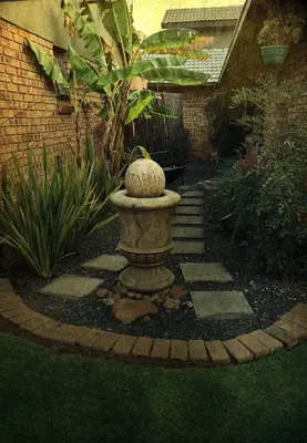 a garden with a stone bird bath in the grass at Revenir in Middelburg