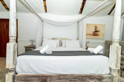 a bedroom with a bed with white sheets and pillows at Bolivia Lodge in Polokwane