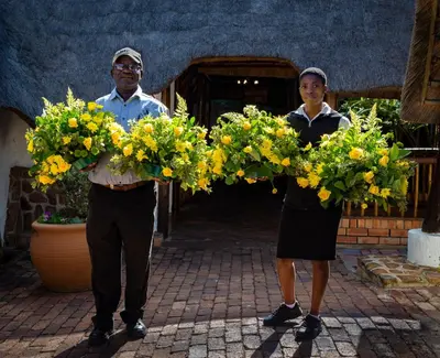 two people are holding a bunch of yellow flowers at Bolivia Lodge in Polokwane