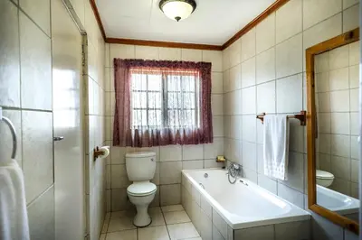 a bathroom with a toilet and a tub and a sink at Bolivia Lodge in Polokwane