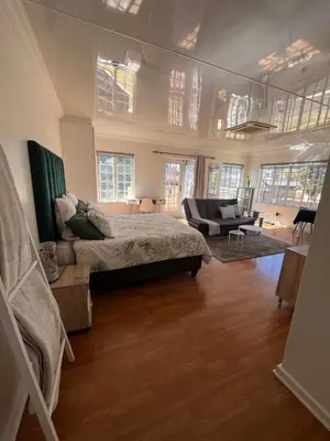 a bedroom with a bed and a living room at Charming Urban Retreat in Centurion