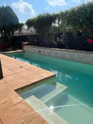 a swimming pool with blue water in a yard at Charming Urban Retreat in Centurion