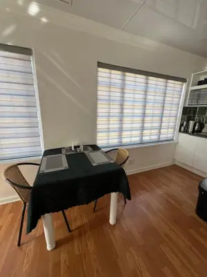 a dining room with a table and two windows at Charming Urban Retreat in Centurion